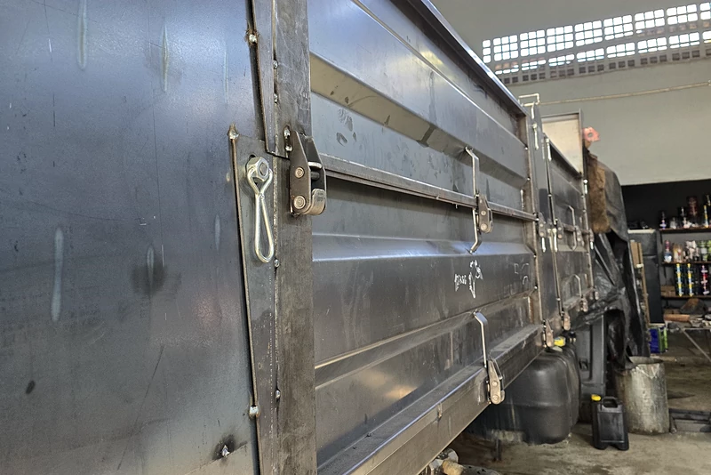 Detalhe da lateral de uma caçamba com os vincos de dobra retos e o fecho de alavanca
