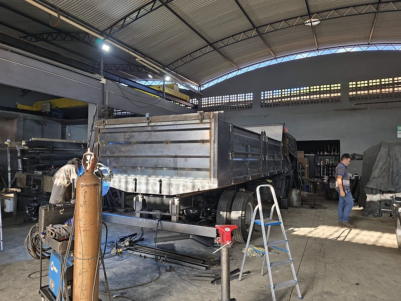 Galpão da JC com caminhão em montagem e caçamba em fabricação